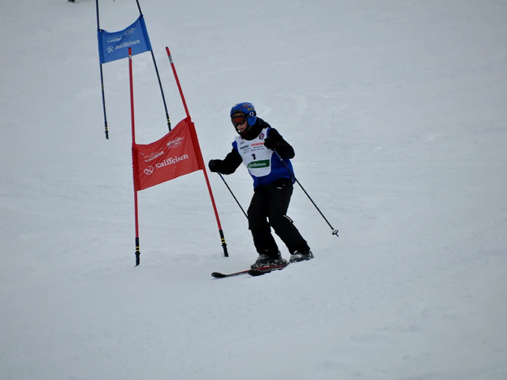 Skifahrer umfährt beim Rennen ein rotes Tor.